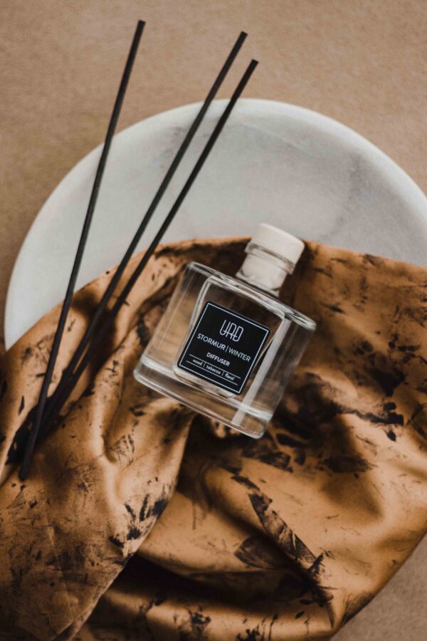 URÐ STORMUR home diffuser with black rattan sticks, featuring a winter scent of tobacco, wood, jasmine, and musk.